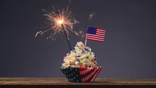 Cupcake American Flag. Sparklers Or Fireworks Lights Burning In A Cake. 4th Of July, Independence, Presidents Day. Tasty Cupcakes With White Cream Icing And Colored Stars Sprinkles. Sweet Dessert.