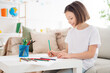 © deagreez - Profile side photo of young cheerful attractive little girl happy positive smile sit sofa draw paint colorful pencils indoors