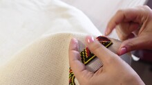 A Woman Embroiders An Ornament With Beads.