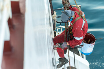 Wall Mural - Seaman ship crew working aloft at height derusting and getting vessel ready for painting.