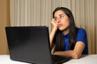 © Kharhem - Woman sitting in front of her laptop. staring at the screen, bored, sleepy, tired. Latin woman in front of her laptop without spirits.