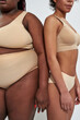 © Svitlana - Cropped shot of two african american women in beige underwear with different weight standing close to each other isolated over gray background