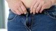 © Kyrylo Ryzhov - Closeup of woman with big belly pulling jeans and struggling to button up. Concept of excessive weight, obese female, dieting and overweight problems