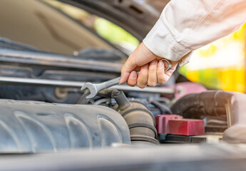 Close up of auto mechanic with hand holding hand wrench in car repair station.