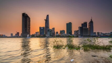 Wall Mural - Time lapse riverside city sunset sky and night brighter coal sparkling skyscrapers along beautiful river in Ho Chi Minh City, Vietnam