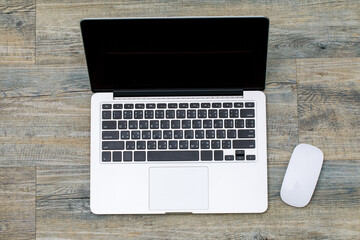 Top view of laptop notebook computer with white mouse on wooden pattern background with copy space