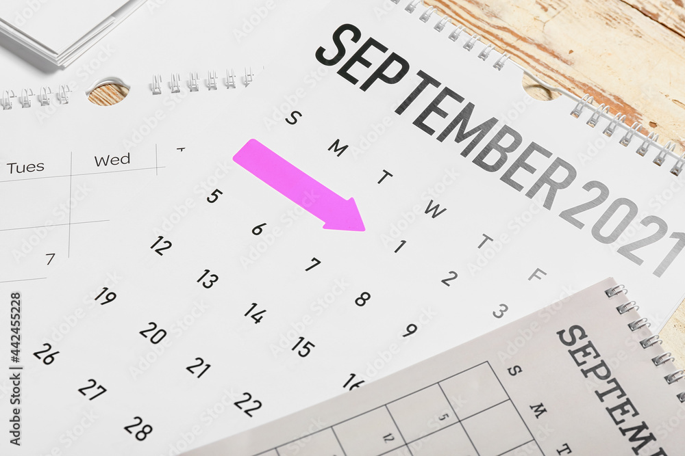 Flip paper calendars on light wooden background, closeup