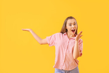 Sticker - Surprised young woman showing something on color background