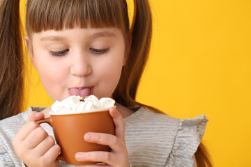 Wall Mural - Little girl drinking hot cocoa on color background, closeup