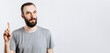 © Daria Lukoiko - Portrait of cheerful young handsome man smiling looking at camera pointing finger upwards on white background with space for advertising mock up