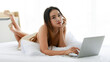© Bangkok Click Studio - Asian woman using laptop on bed