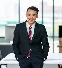 Cheerful Asian businessman standing in workplace