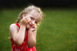 © stopabox - Portrait of a happy cute little girl in a field in the red dress on green grass background