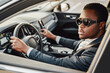 © Fxquadro - Stylish black businessman inside of car holding wheel
