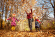 © keleny - Two young little girl and his mother with blonde hair in an autumn park on a yellow and orange leaf background. Family walking in forest