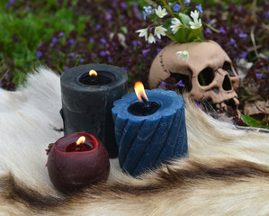 Beltane ritual with burning candles and skull with flowers outside.