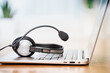 Laptop. Close up of headphones or headset on desk and plain background banner. Distant learning or working from home, online courses or customer support minimal concept. Helpdesk or call center