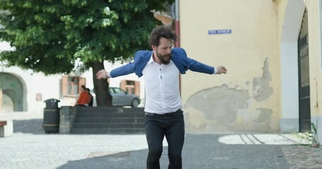 Poster - confident bearded guy looking to side, adjusting blue jacket, dancing, making dynamic moves and celebrating victory outside in medieval city