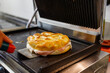 Focaccia ligure rotonda ripiena di prosciutto e formaggio in cottura sulla piastra