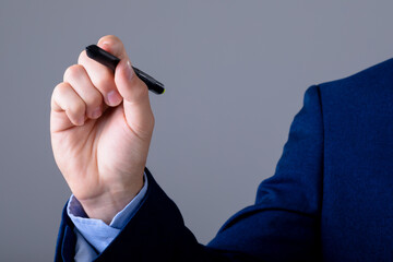 Midsection of caucasian businessman holding marker, isolated on grey background