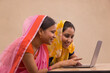 Two rural women sitting together with a laptop.