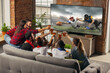 © master1305 - Leisure time. Excited, happy big group of young people watching sport match together on the couch at home.