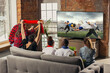 © master1305 - Leisure time. Excited, happy big group of young people watching sport match together on the couch at home.