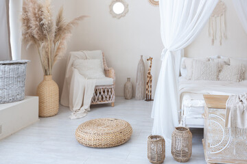 daylight through a huge panoramic window illuminates the cozy oriental interior of the room in beige colors with wicker furniture and authentic elements