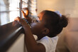 © Wavebreak Media - Curious african american girl standing and peering through window blinds on a sunny day