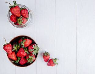 top view of fresh ripe strawberries in a wooden bowl on white background with copy space