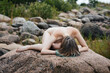 Nude woman enjoying nature among stones by the sea