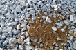 Graue kleine Steine mit einem kontrastreichen Erdhaufen in der Mitte. Hintergrund für Schutt und Dreck. Gravel und Sand.
