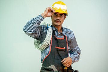 Poster - Technician in safety helmet holding electric cable with tools working on a construction site.