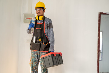 Poster - Technician in safety helmet holding electric cable with tools working on a construction site.