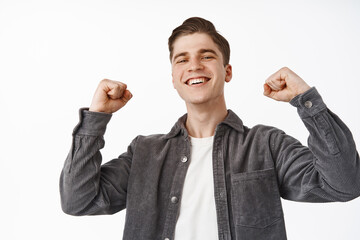 Wall Mural - Yes win. Successful young man cheering, celebrating and chanting, raising hands up fist pumps and smiling satisfied, winning bet, watching game competition and rooting for team