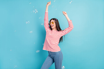 Sticker - Portrait of attractive dreamy cheerful girl dancing having fun bubbles flying isolated over bright blue color background