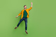 Full size photo of handsome mature man happy positive smile try to catch umbrella jump isolated over green color background