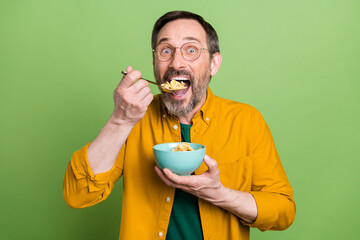 Poster - Photo of mature man happy positive smile eat cornflakes lunch tasty isolated over green color background