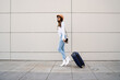 © Mego-studio - Young woman carrying a suitcase outdoors.