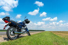 A Motorcycle Trip Through The Countryside In The Summer. A Blue Motorcycle On A Background Of Blue Sky And White Clouds.