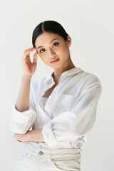 Asian woman in white clothes looking at camera isolated on grey