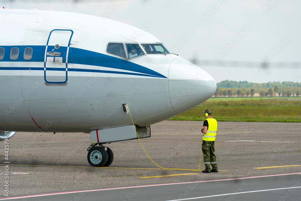 Foto An airport employee in special clothes and headphones conducts pre ...