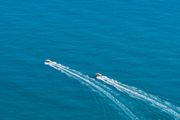 Top view of two boats sailing at high speed. Aerial view of boats in motion on blue water.