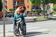 © ADDICTIVE STOCK - Aged mother in wheelchair and adult daughter walking in city