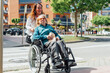 © ADDICTIVE STOCK - Aged mother in wheelchair and adult daughter walking in city