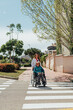 © ADDICTIVE STOCK - Aged mother in wheelchair and adult daughter walking in city