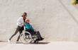 © ADDICTIVE STOCK - Woman walking with aged mother in wheelchair in street