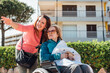 © ADDICTIVE STOCK - Aged mother in wheelchair and adult daughter walking in city