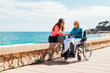 © ADDICTIVE STOCK - Daughter and senior mother in wheelchair on promenade