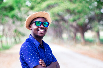 Wall Mural - African man is wearing hat and sunglasses with the green nature background